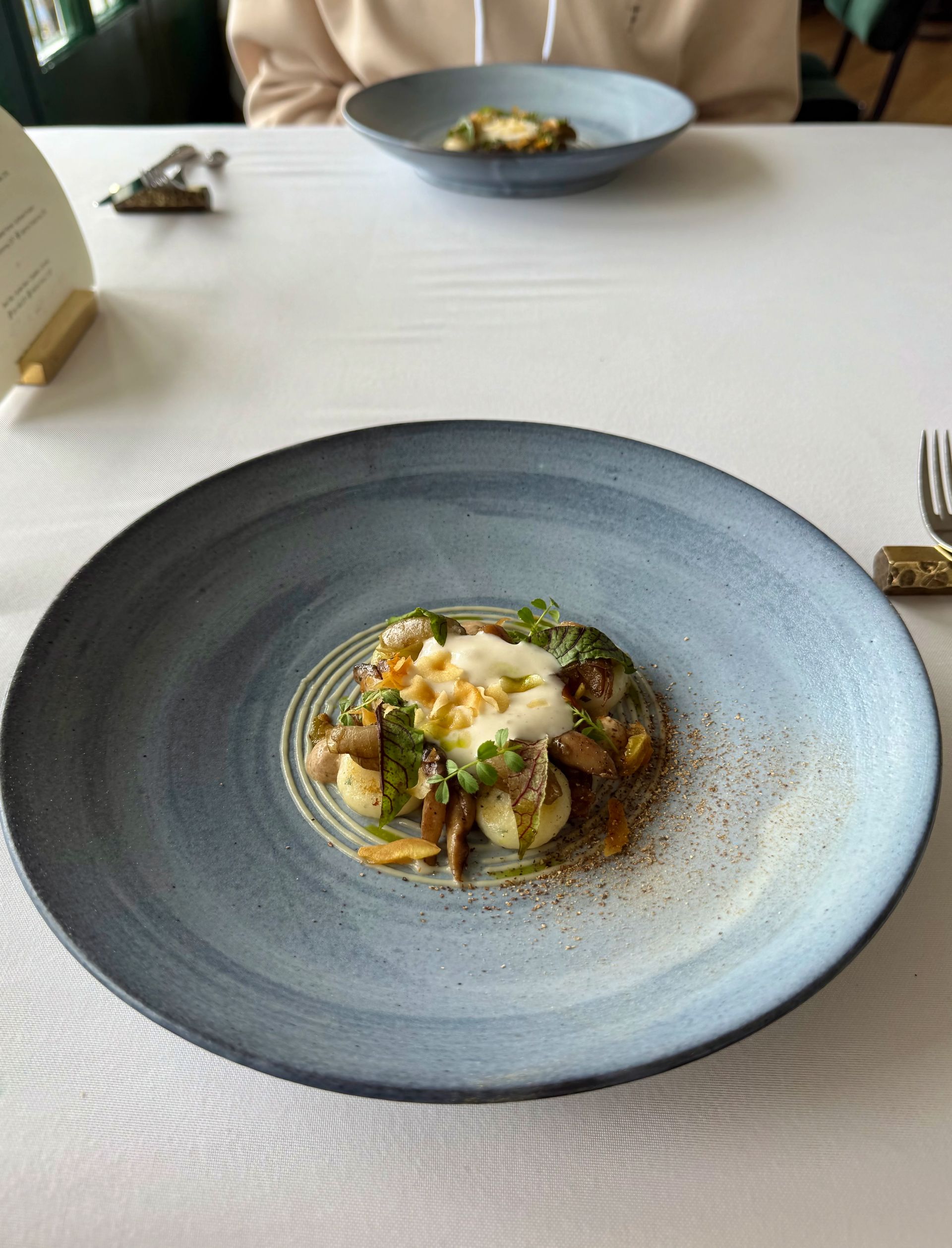 A plate of food, featuring a main dish with mushrooms and garnish, on a table.