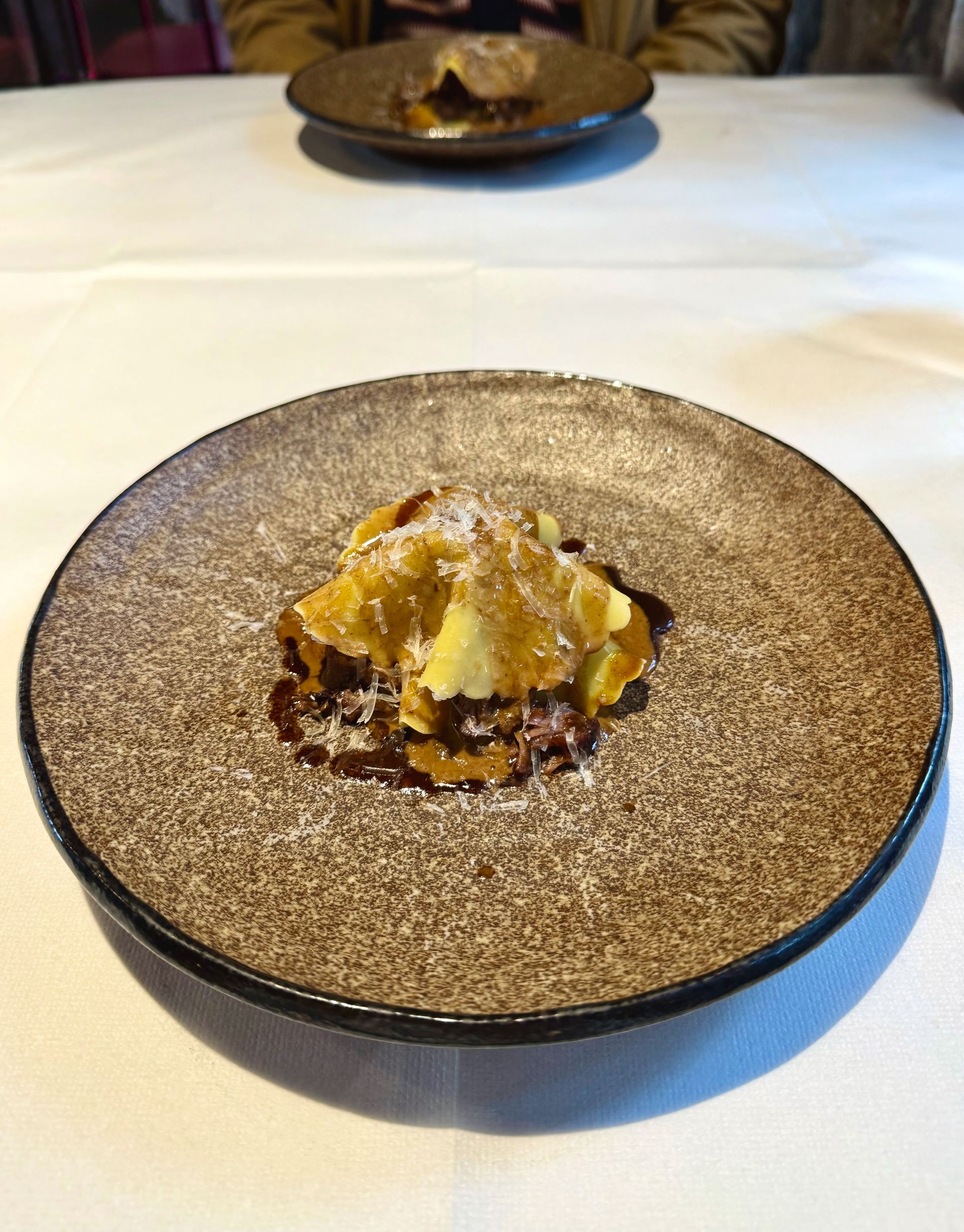 Dessert on a speckled brown plate, dusted with sugar. Another plate in the background.