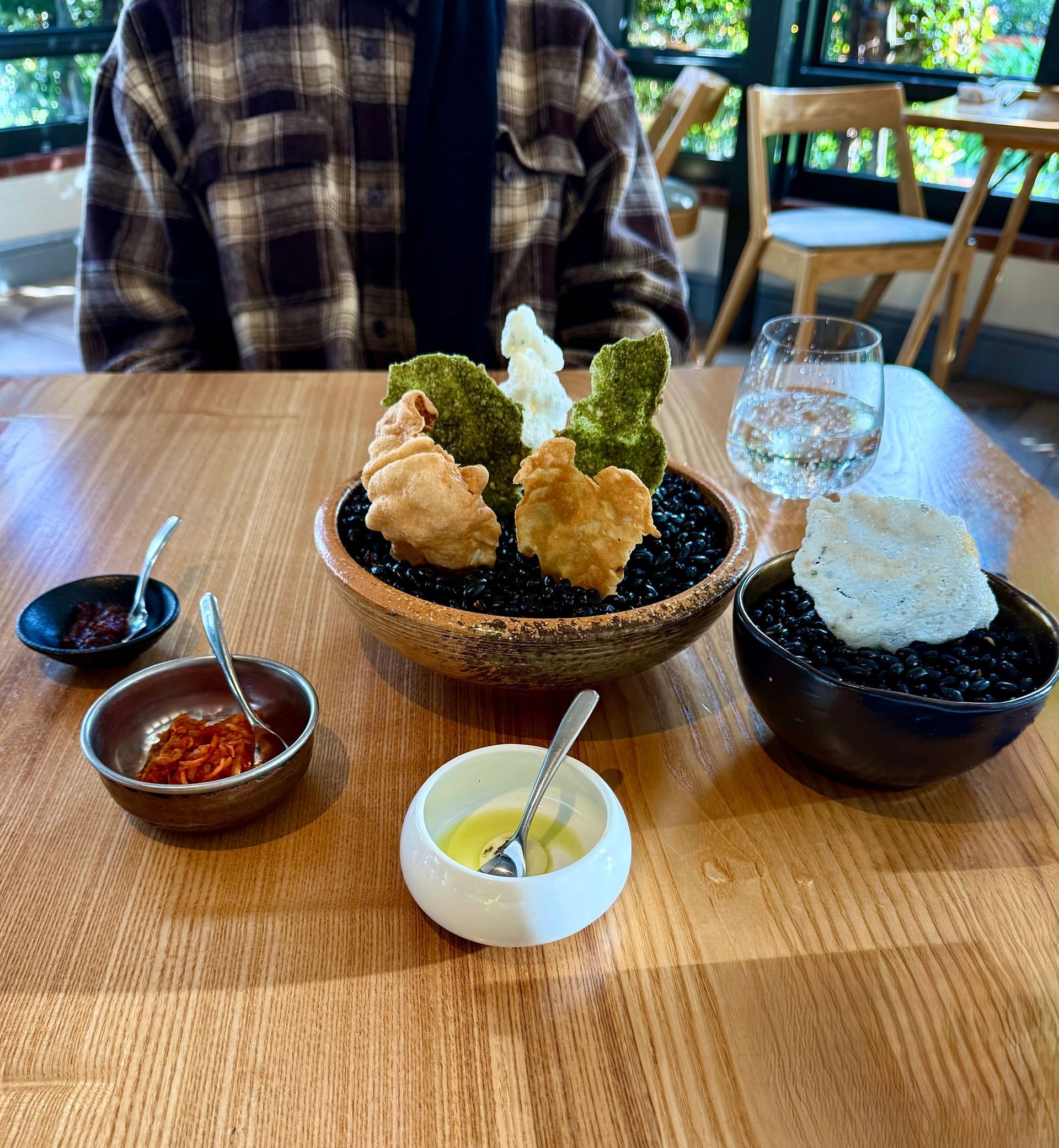 Person at table with a dish of fried food and dipping sauces in a restaurant setting.