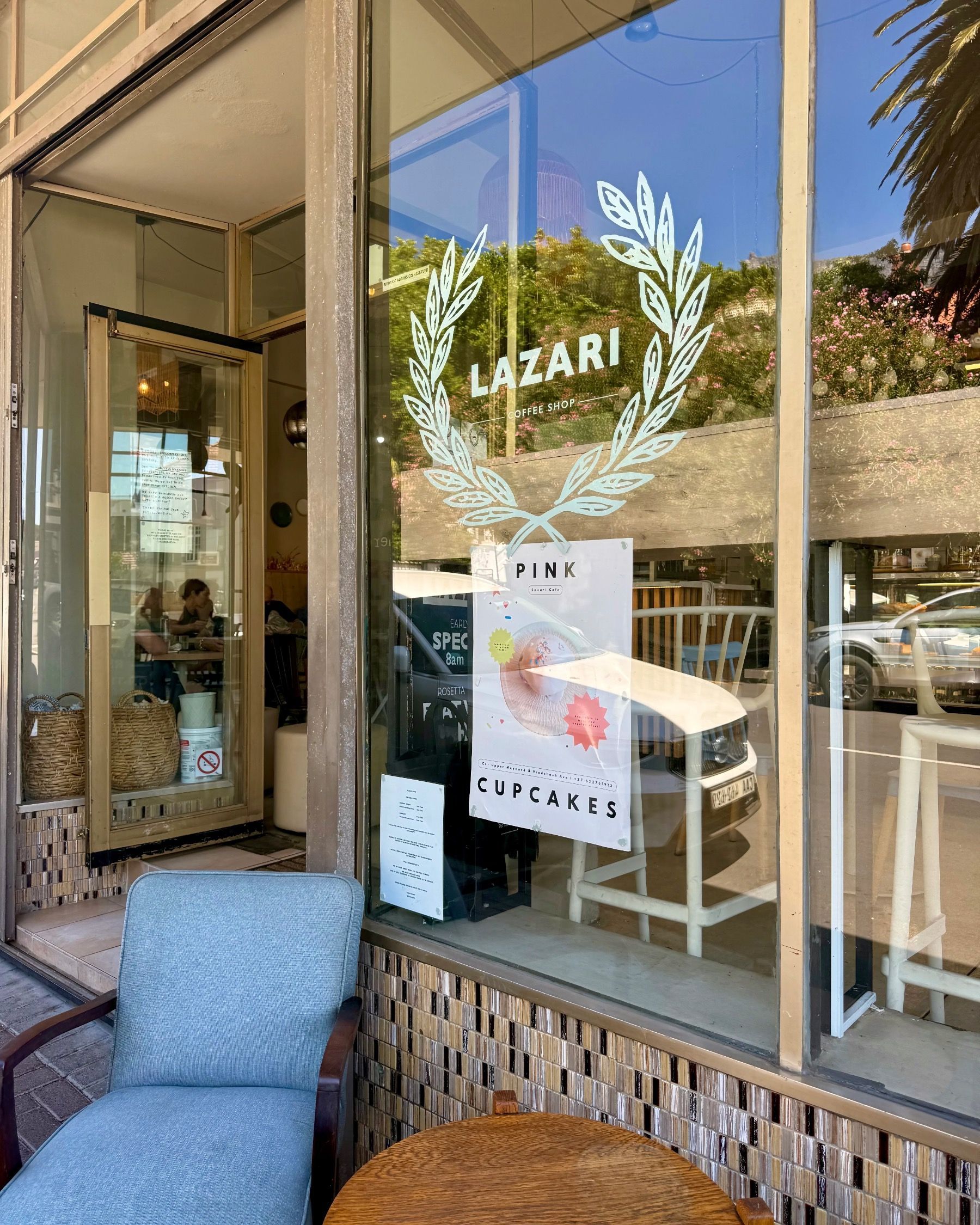 Entrance of Lazari Café in Gardens, Cape Town, with glass frontage and café signage welcoming guests inside