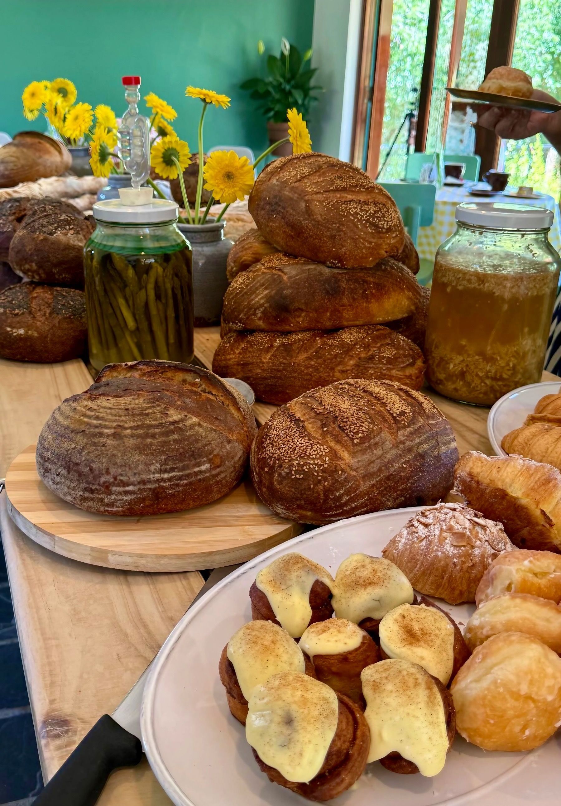 Rustic sourdough loaves, pastries and baked goods displayed on a wooden table at Motherdough bakery in Jonkershoek