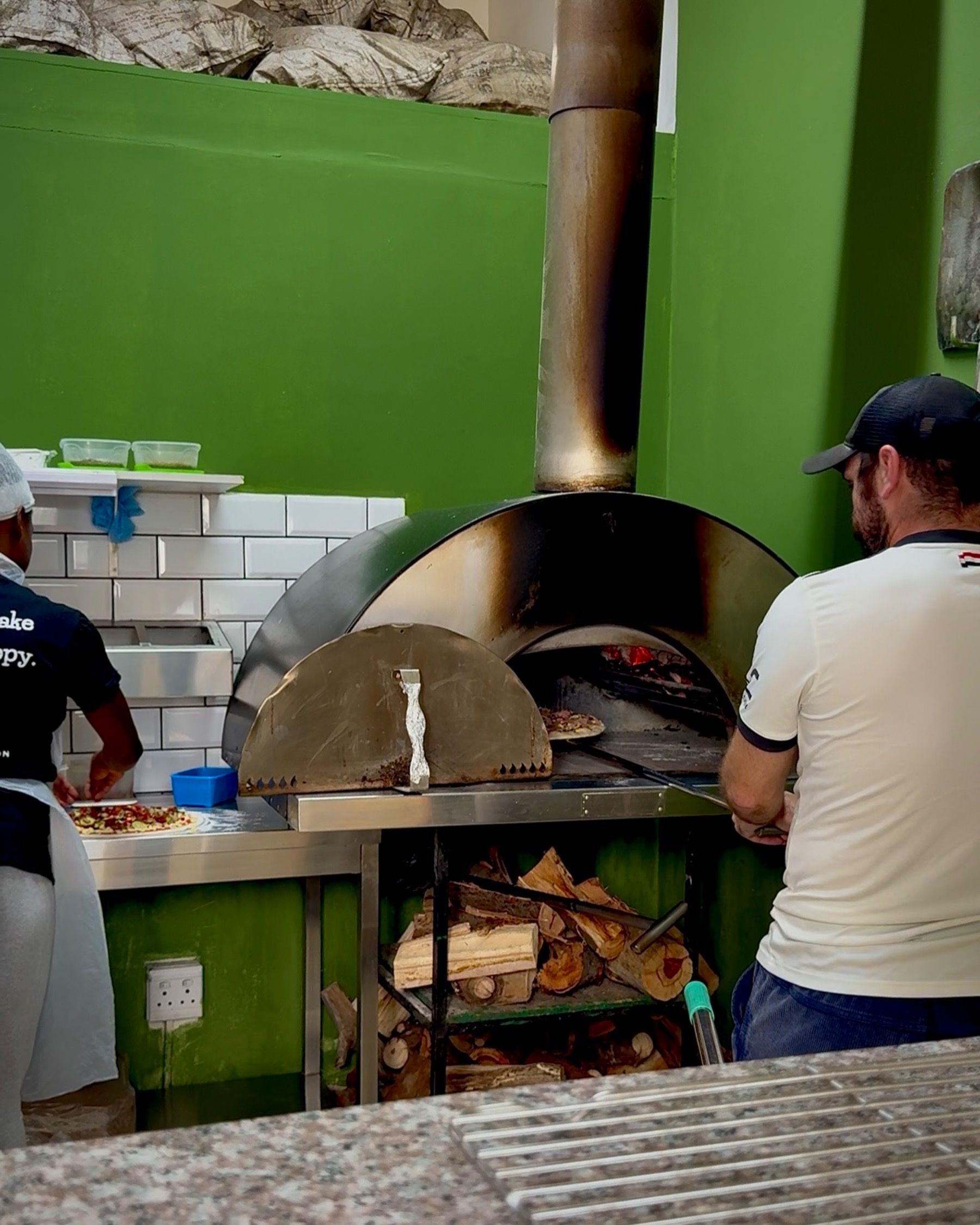 Fresh pizza being prepared in the wood-fired oven at Piccolo Posticino Rondebosch