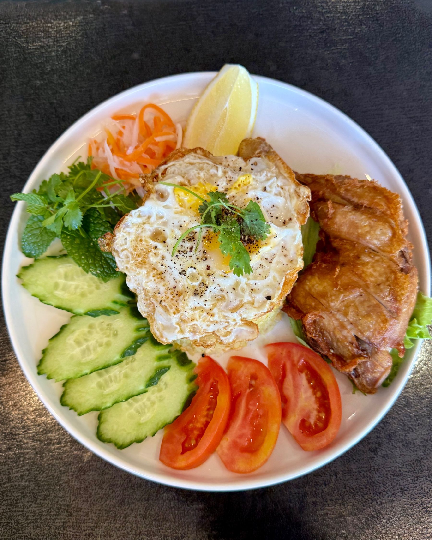 Com Ga with crispy chicken, fried egg, rice and fresh vegetables