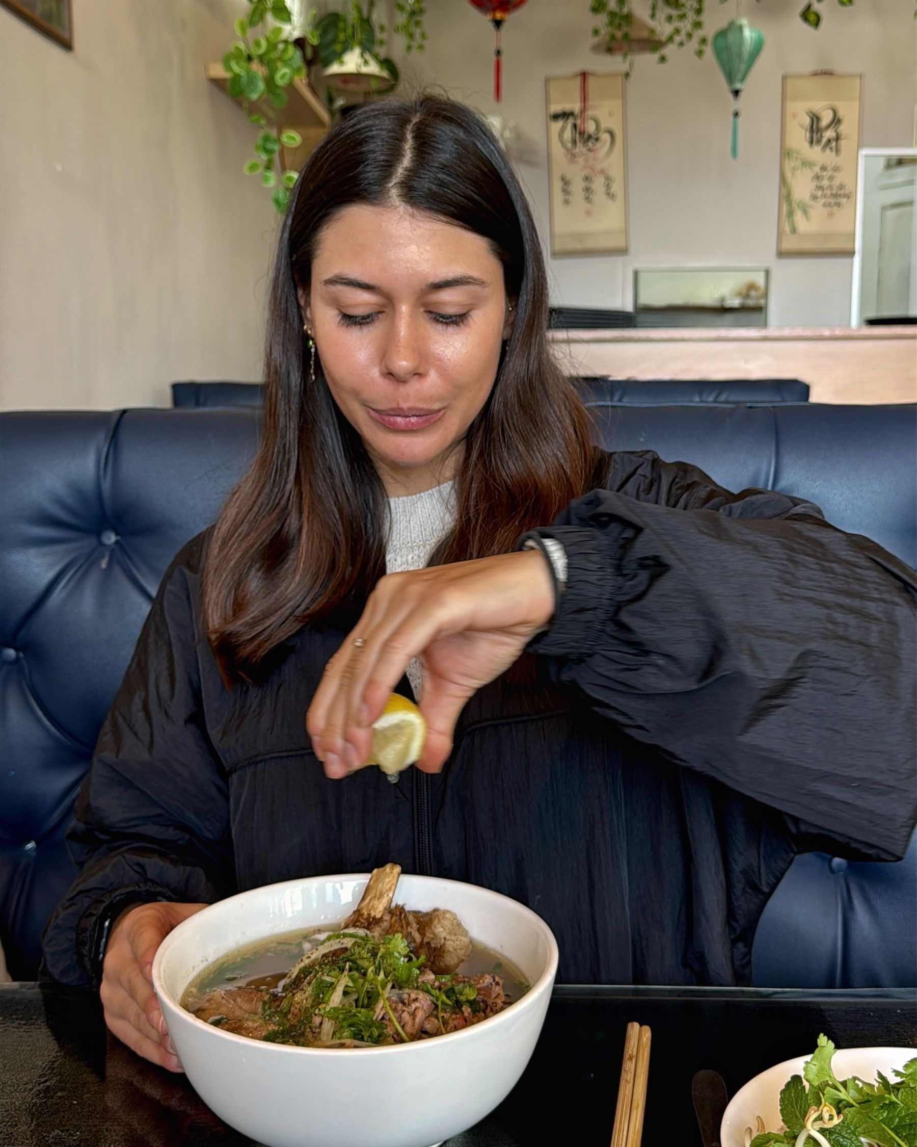 Paige adding lemon to a bowl of beef pho
