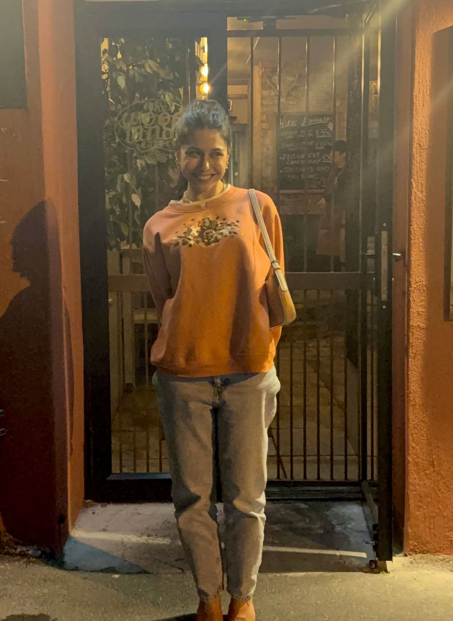 Paige smiling at the entrance of The Woodlands Eatery in Cape Town.
