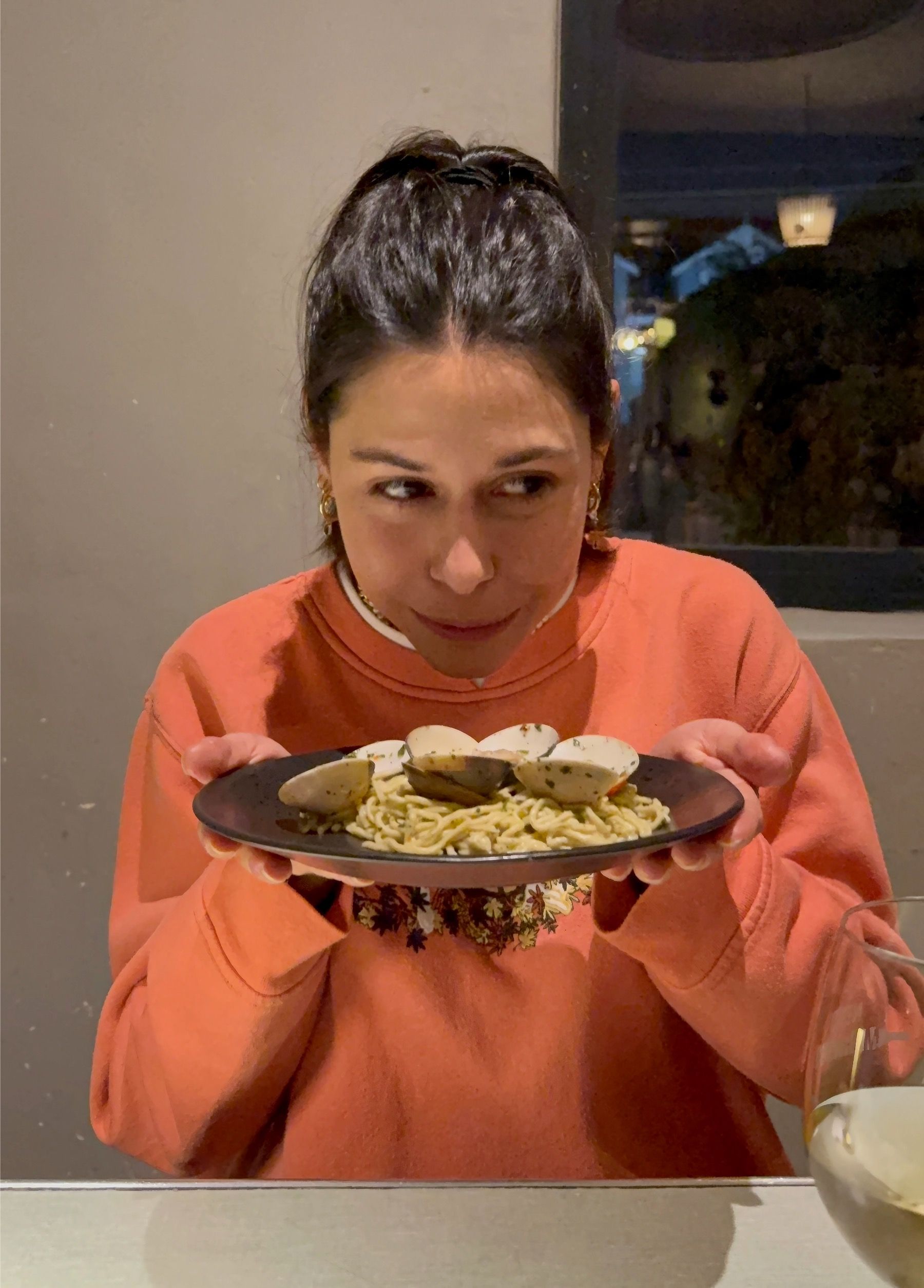 Paige smelling clam pasta at The Woodlands Eatery during a wine pairing evening.
