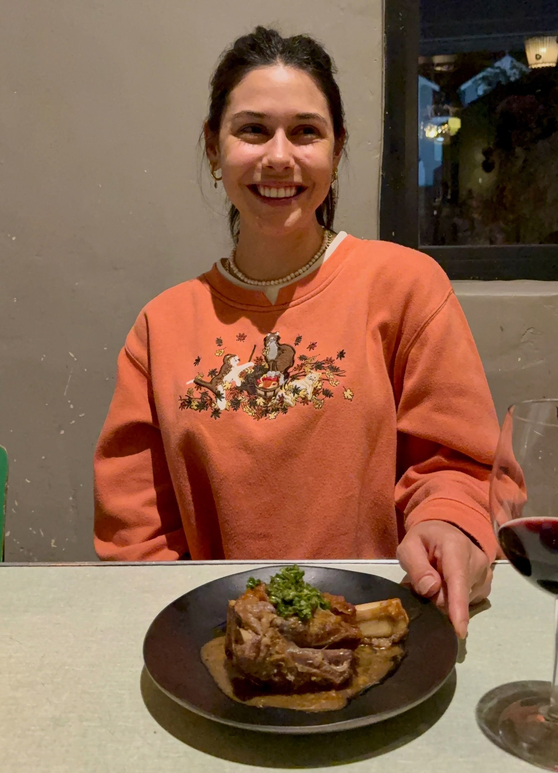 Paige smiling while holding a lamb main course at The Woodlands Eatery wine pairing.
