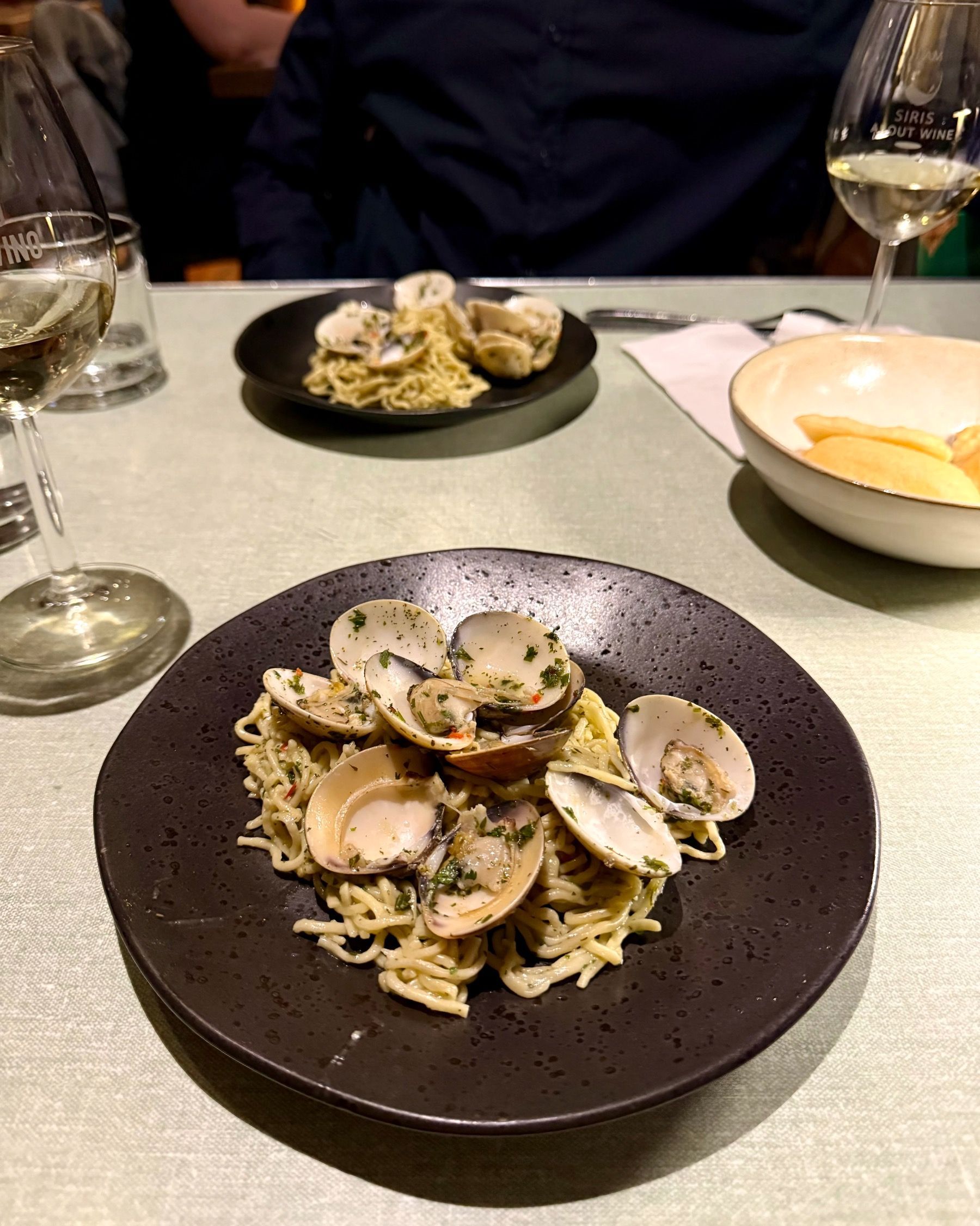 Clam pasta in a dark bowl at The Woodlands Eatery during a Zevenwacht wine pairing dinner.
