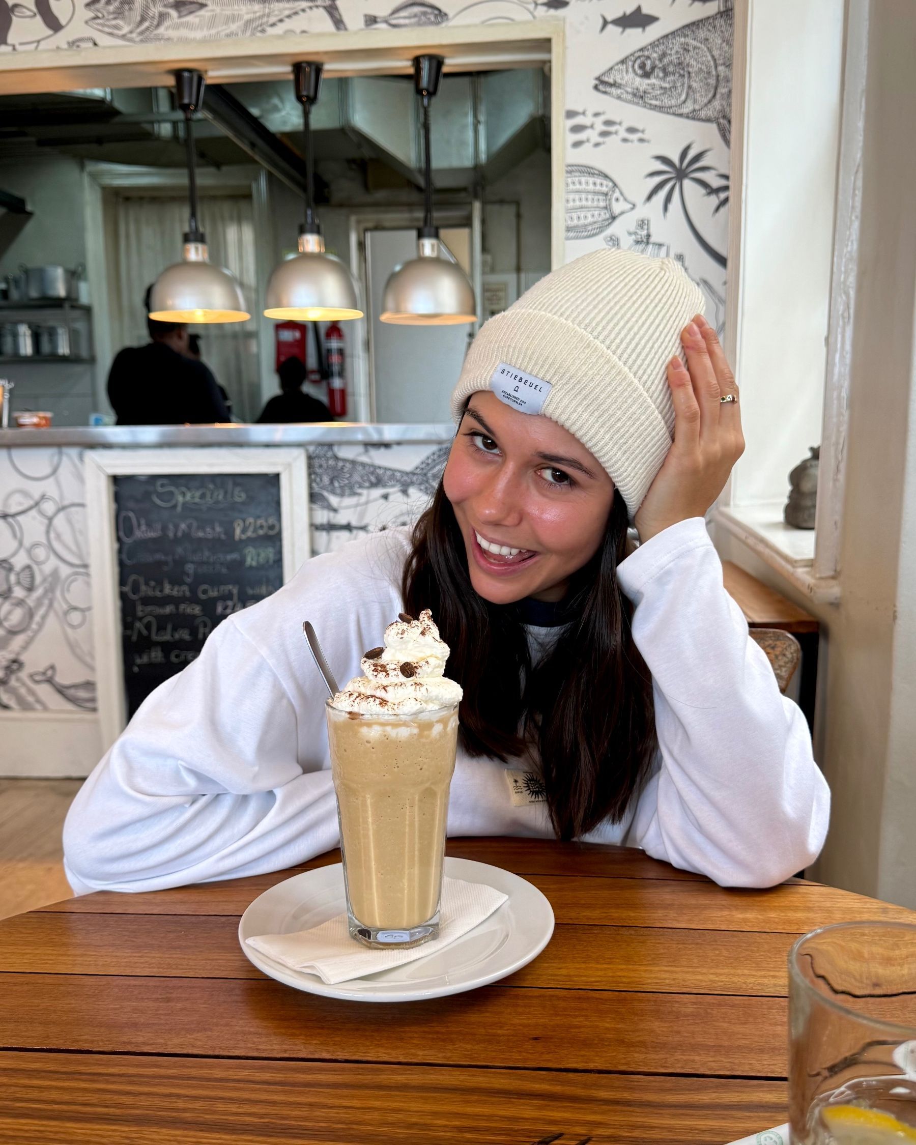 Paige smiling with a coffee milkshake at Dalebrook Café.