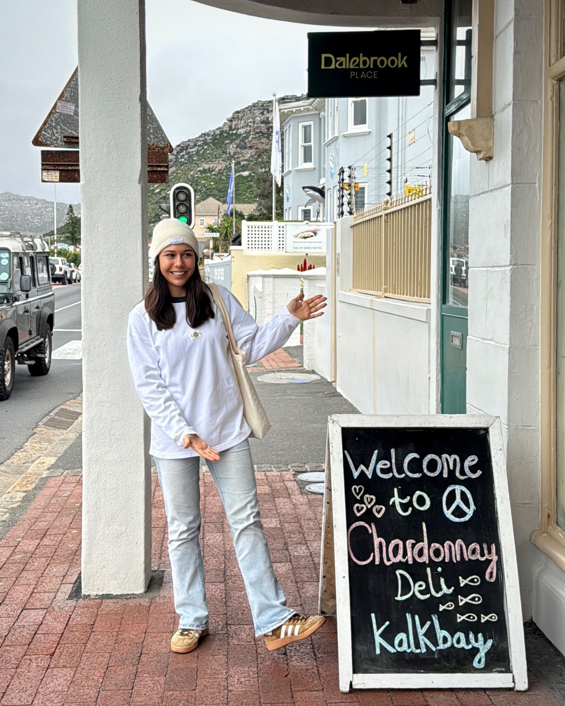 Paige standing next to the Dalebrook Café entrance sign in Kalk Bay.