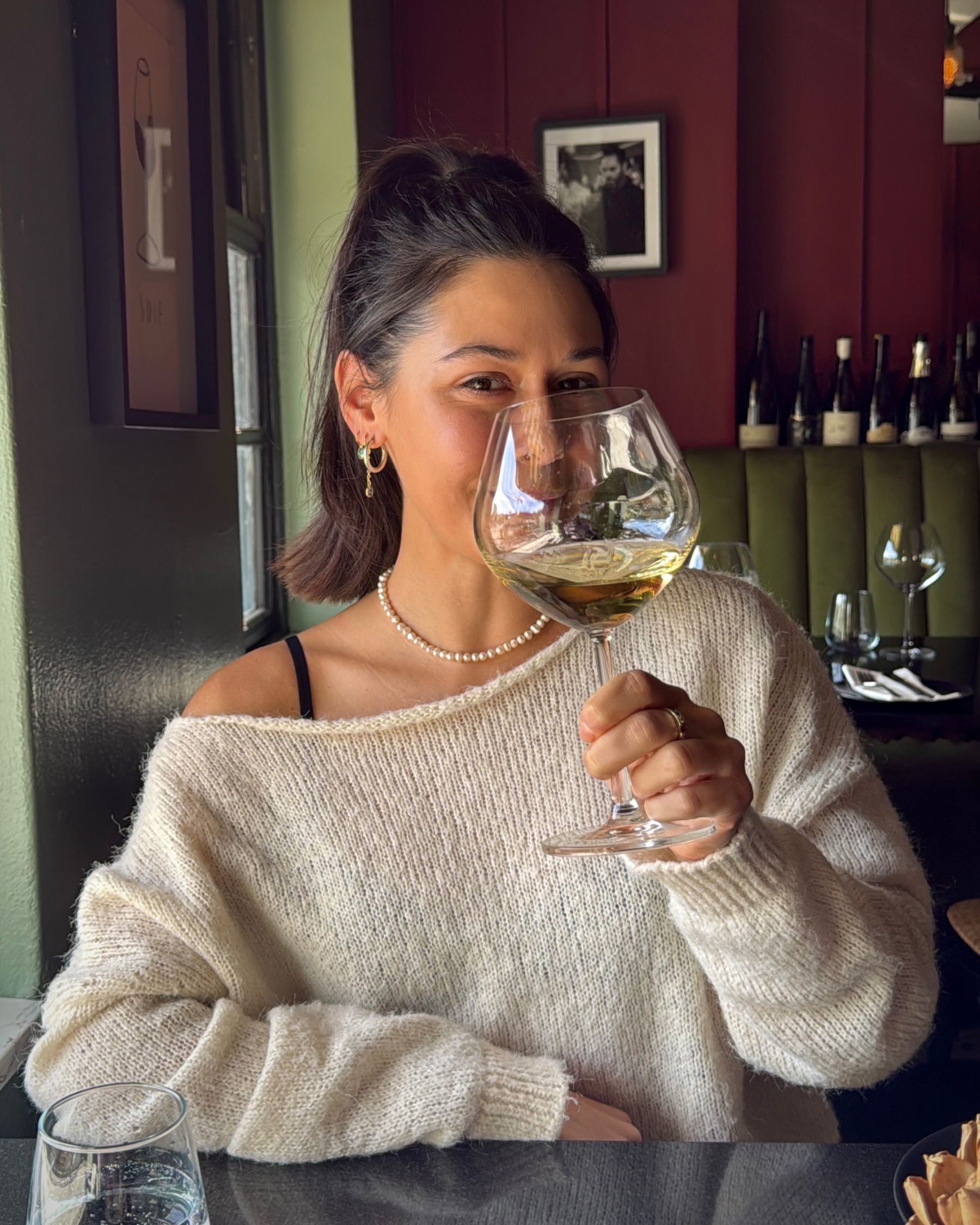 Paige holding a glass of white wine at Grub & Vine.