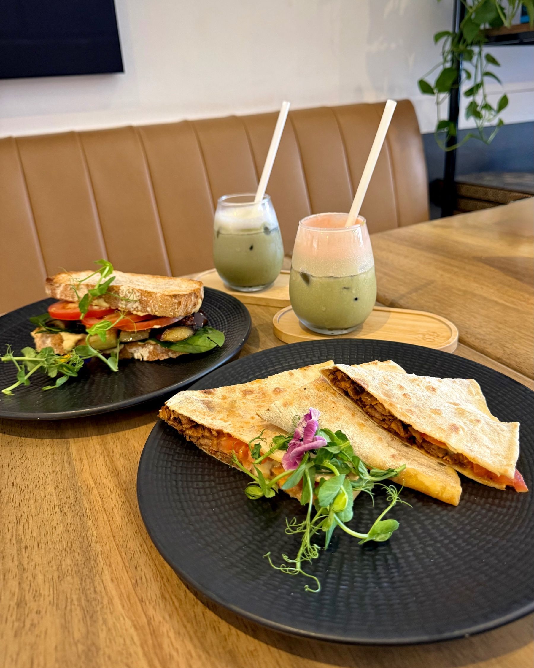 Pulled Beef Flatbread in the foreground with iced matcha and the Mediterranean Sourdough Sandwich behind it.