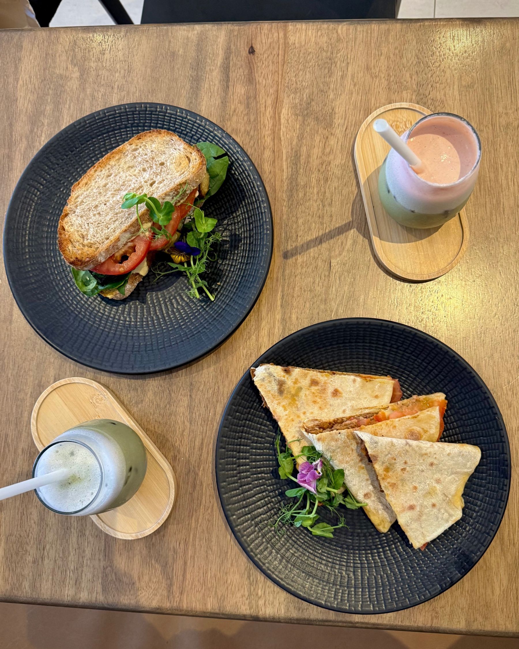 Overhead view of iced matchas, Pulled Beef Flatbread and Mediterranean Sourdough Sandwich at Mischu.