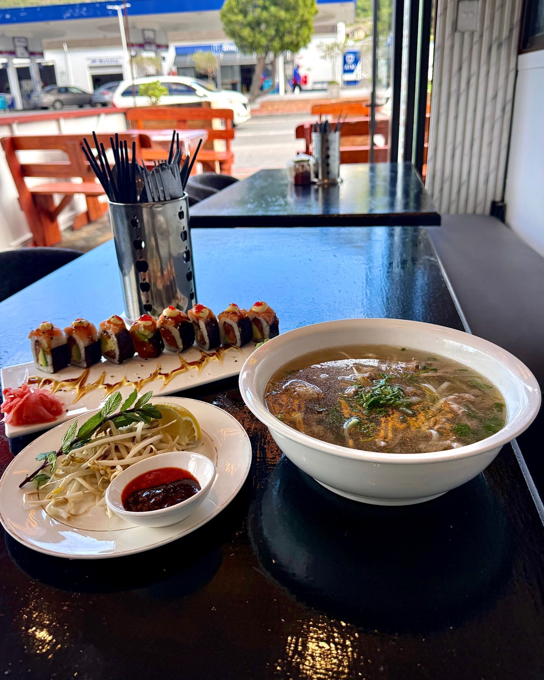 A comforting bowl of beef pho served alongside fresh salmon rainbow rolls at Pho Hue.