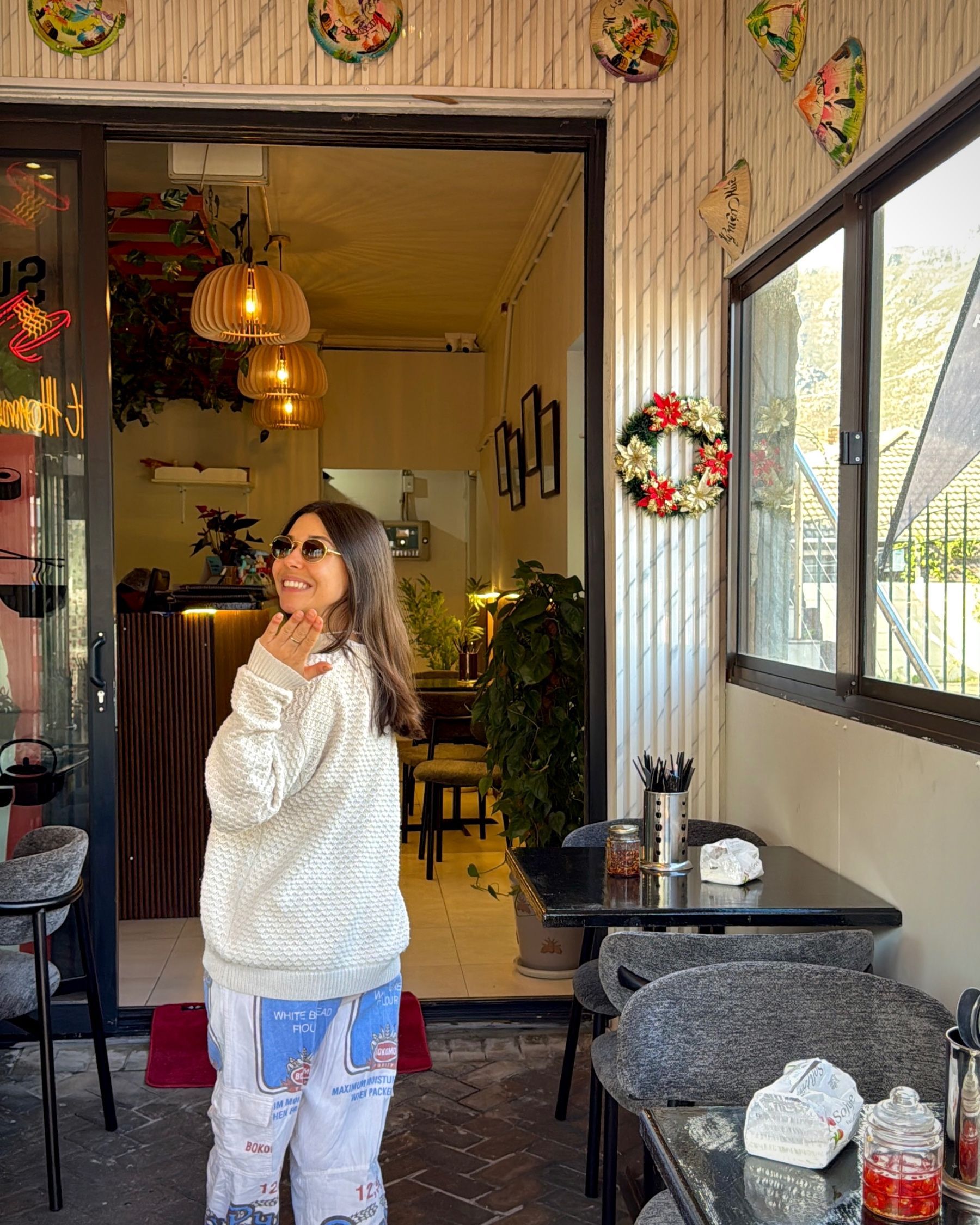 Paige walking into Pho Hue Vietnamese restaurant in Hout Bay, welcoming visitors inside.