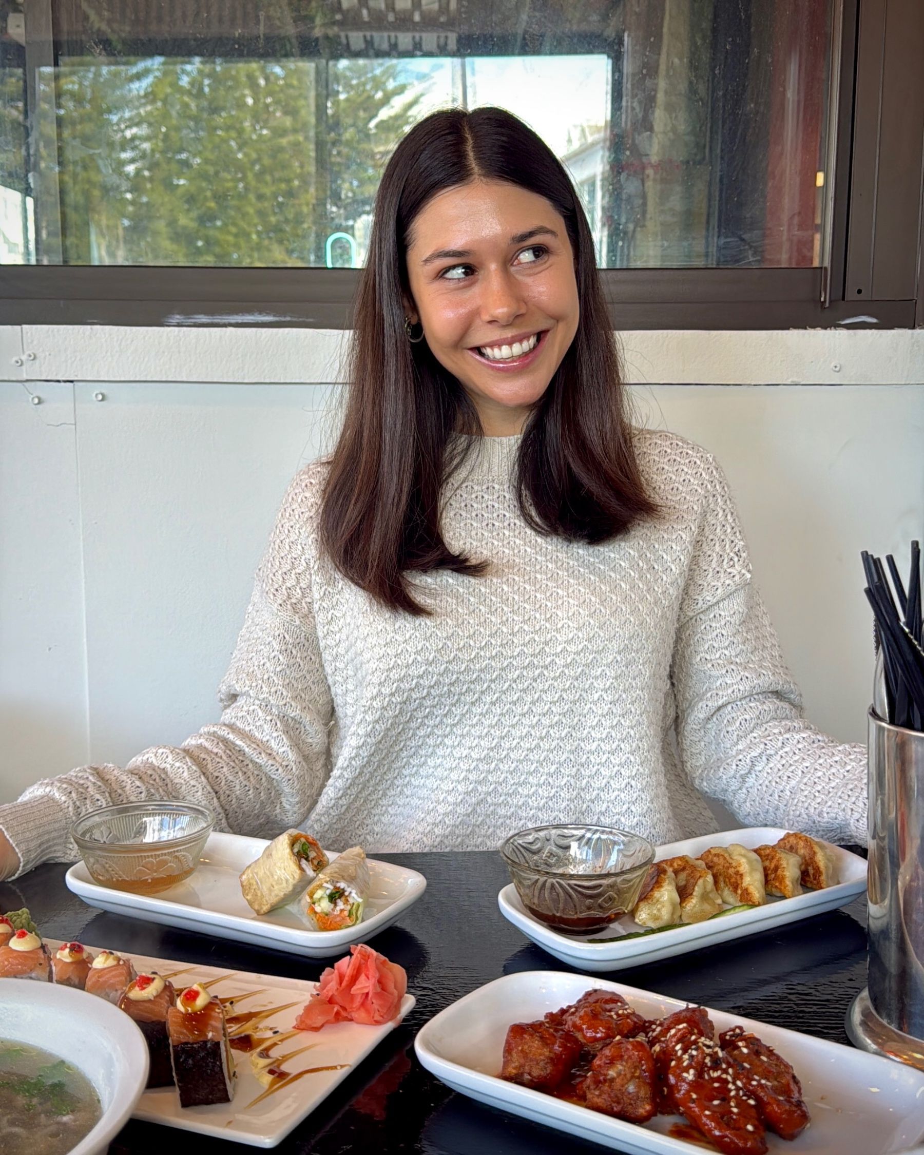 Paige smiling with a table full of authentic Vietnamese dishes at Pho Hue.