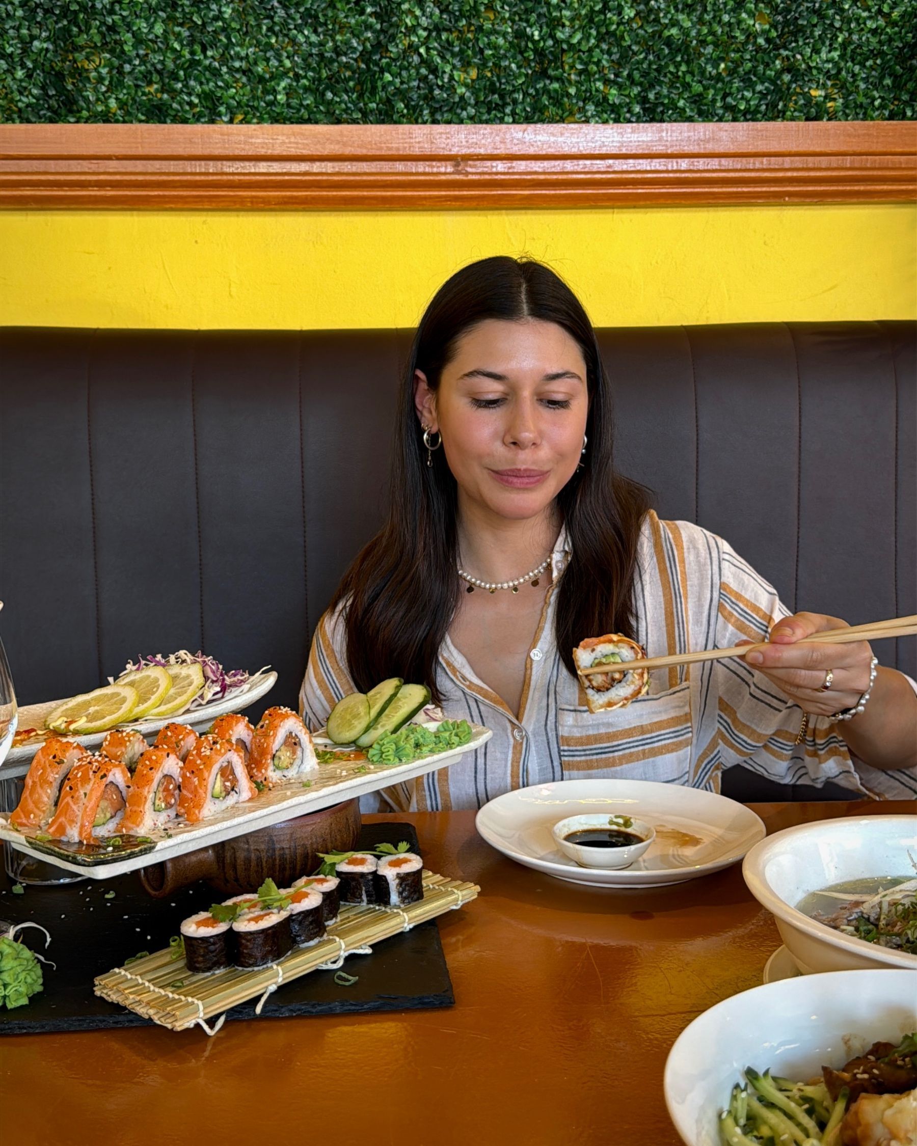 Paige eating a new-style salmon rose with chopsticks at Aiko Sushi Plus.