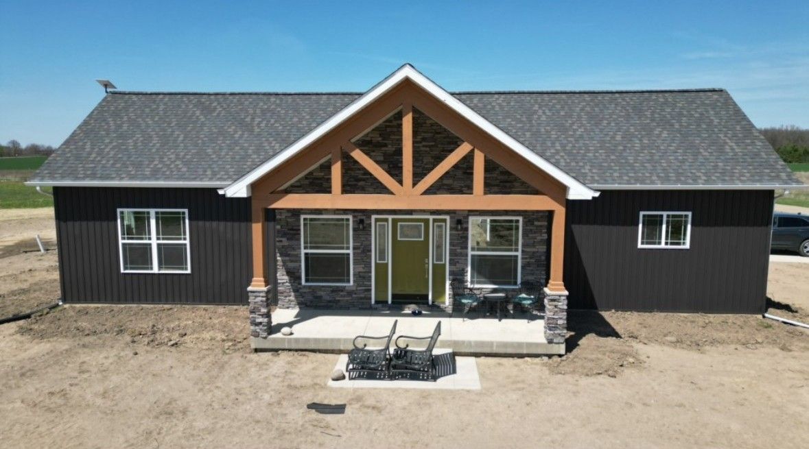 An aerial view of a house with a porch and a car parked in front of it.