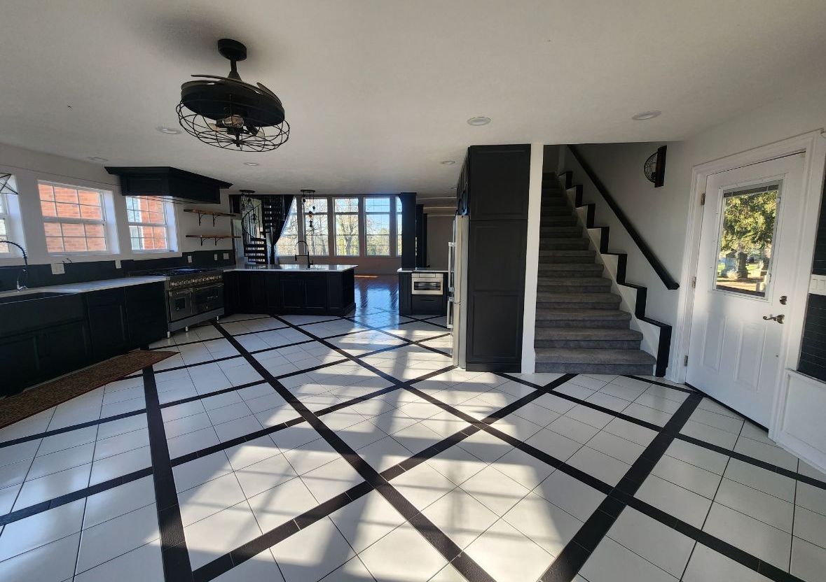 A large room with a black and white tile floor and stairs