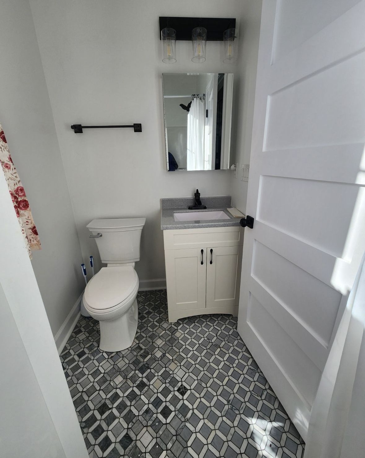 A bathroom with a toilet , sink and mirror.