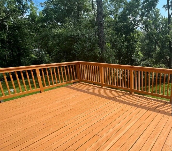 A wooden deck with a railing and trees in the background