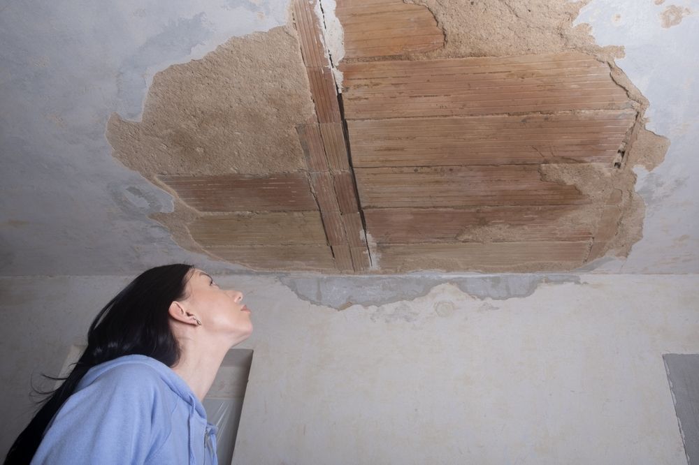 A woman is looking up at the ceiling of a room.