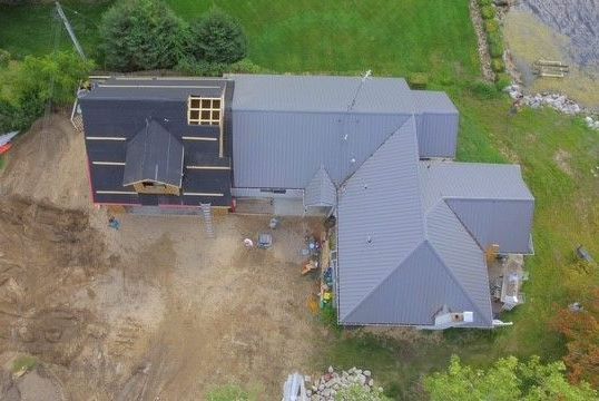 An aerial view of a house under construction in the middle of a field.