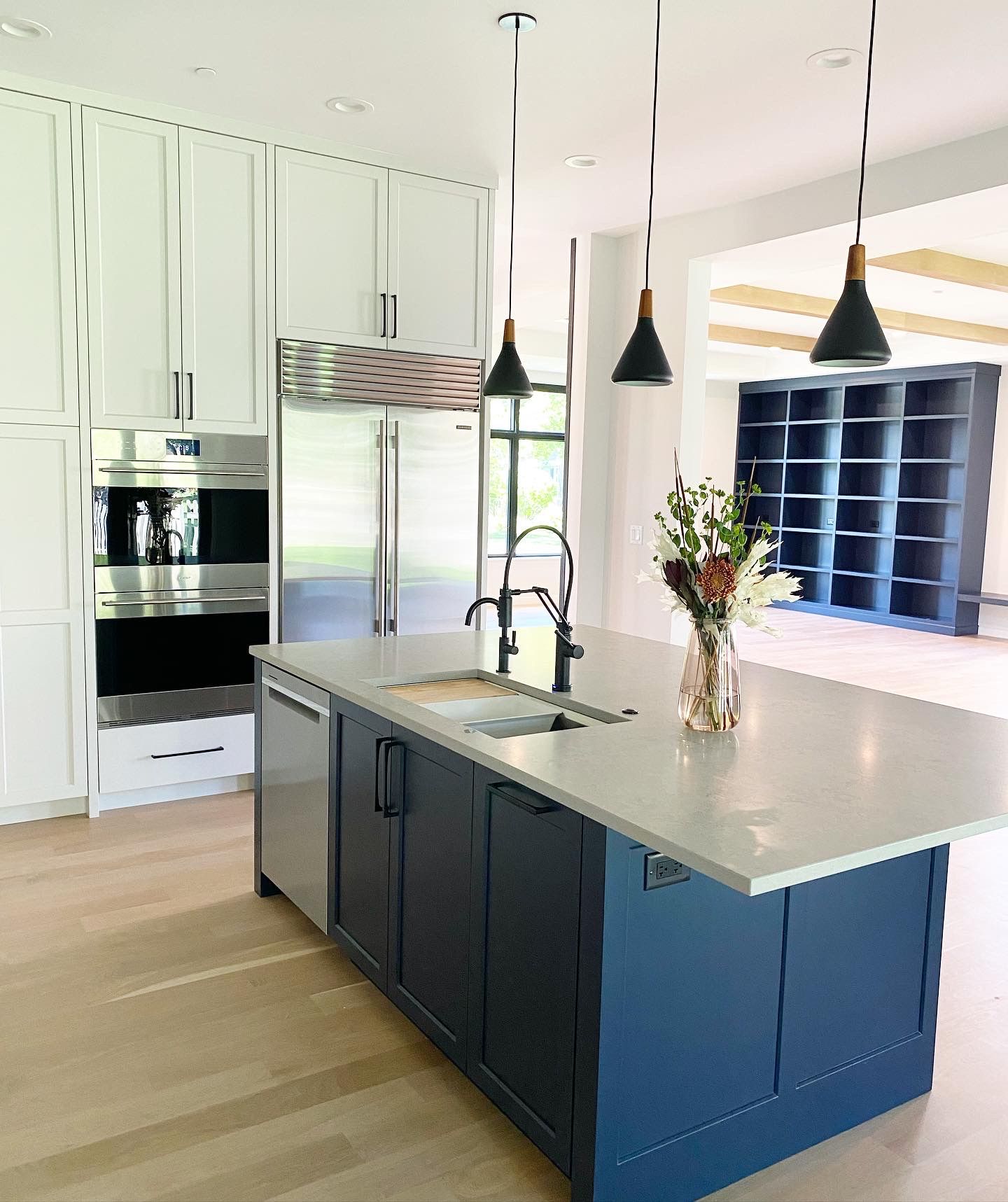 A kitchen with a large blue island and a vase of flowers on the counter.