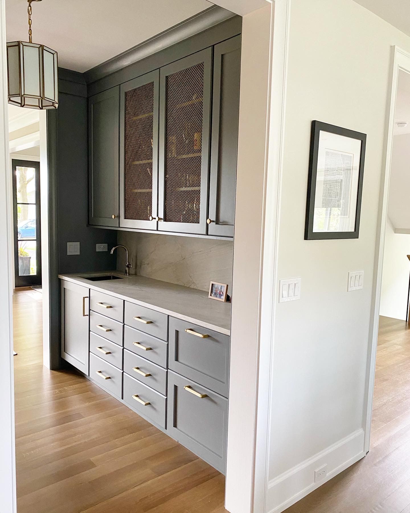 A kitchen with gray cabinets and a wine rack on the wall.