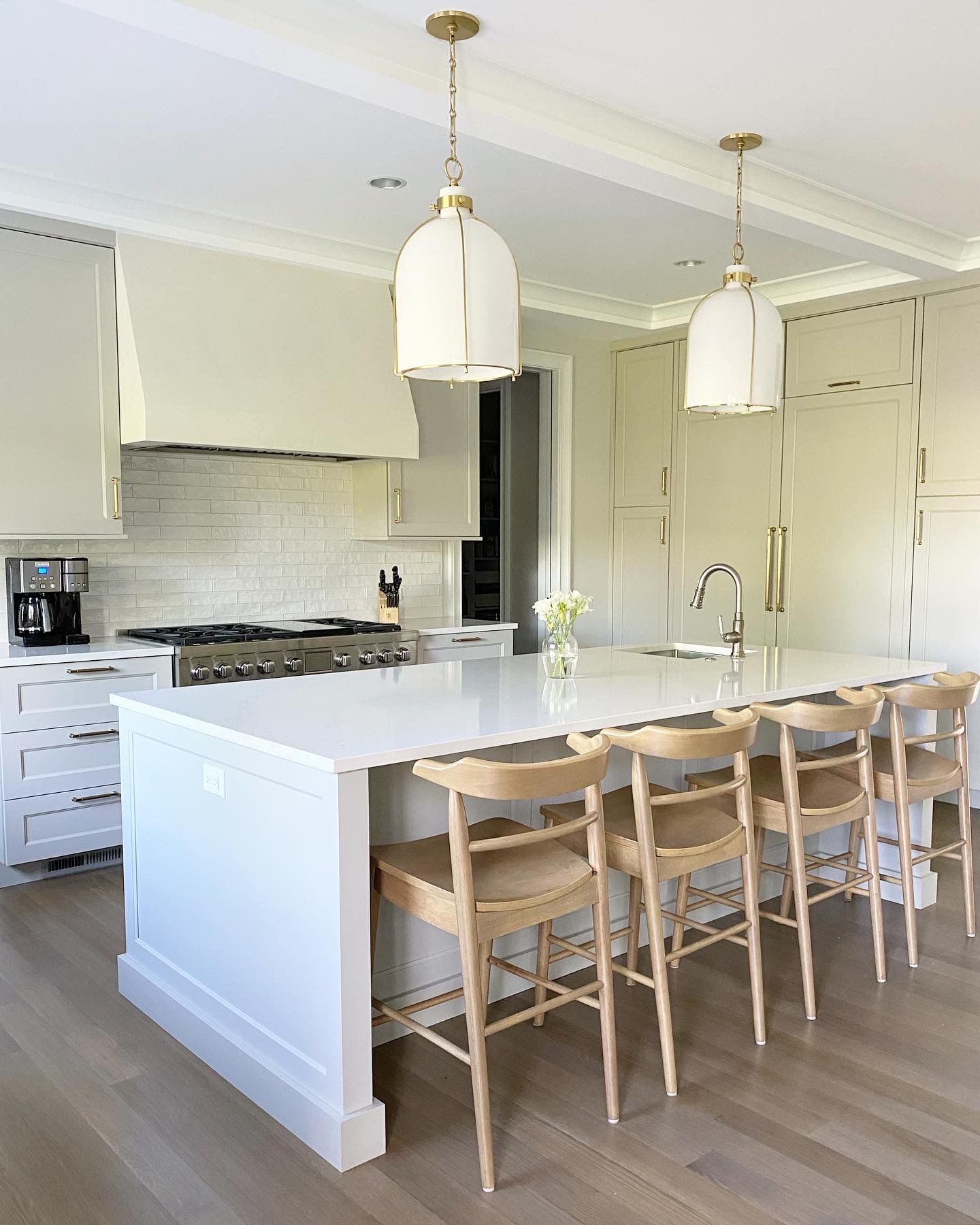 A kitchen with a large island and wooden chairs.