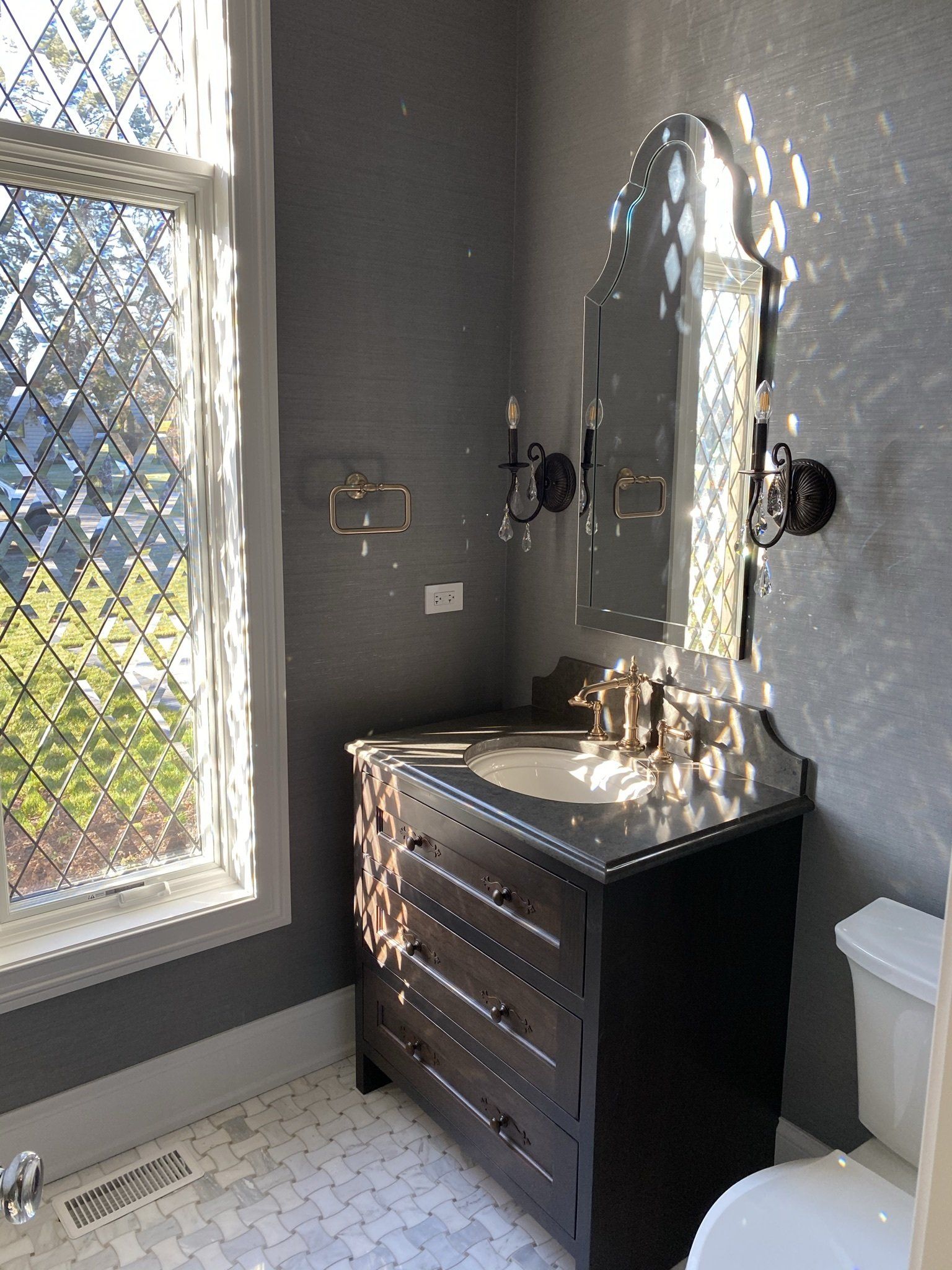 A bathroom with a sink , toilet , mirror and window