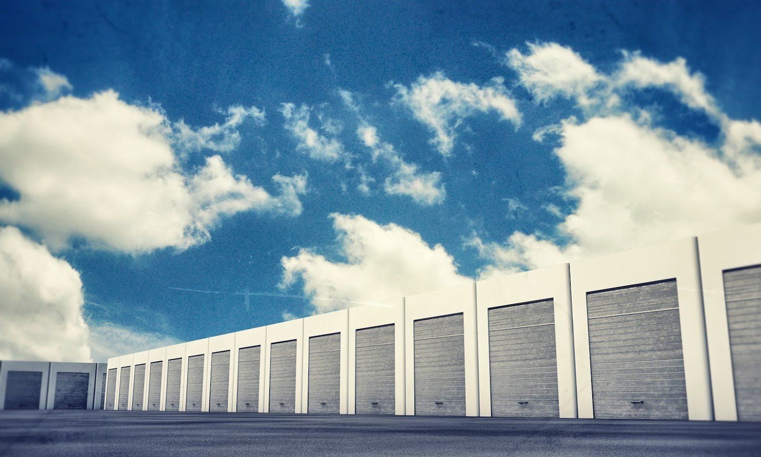 A row of garage doors against a blue sky with clouds