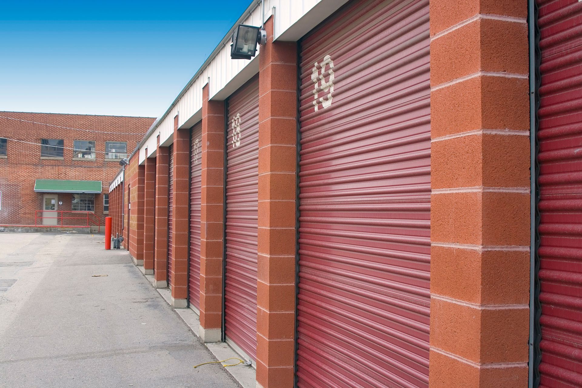 A row of red garage doors on a brick building