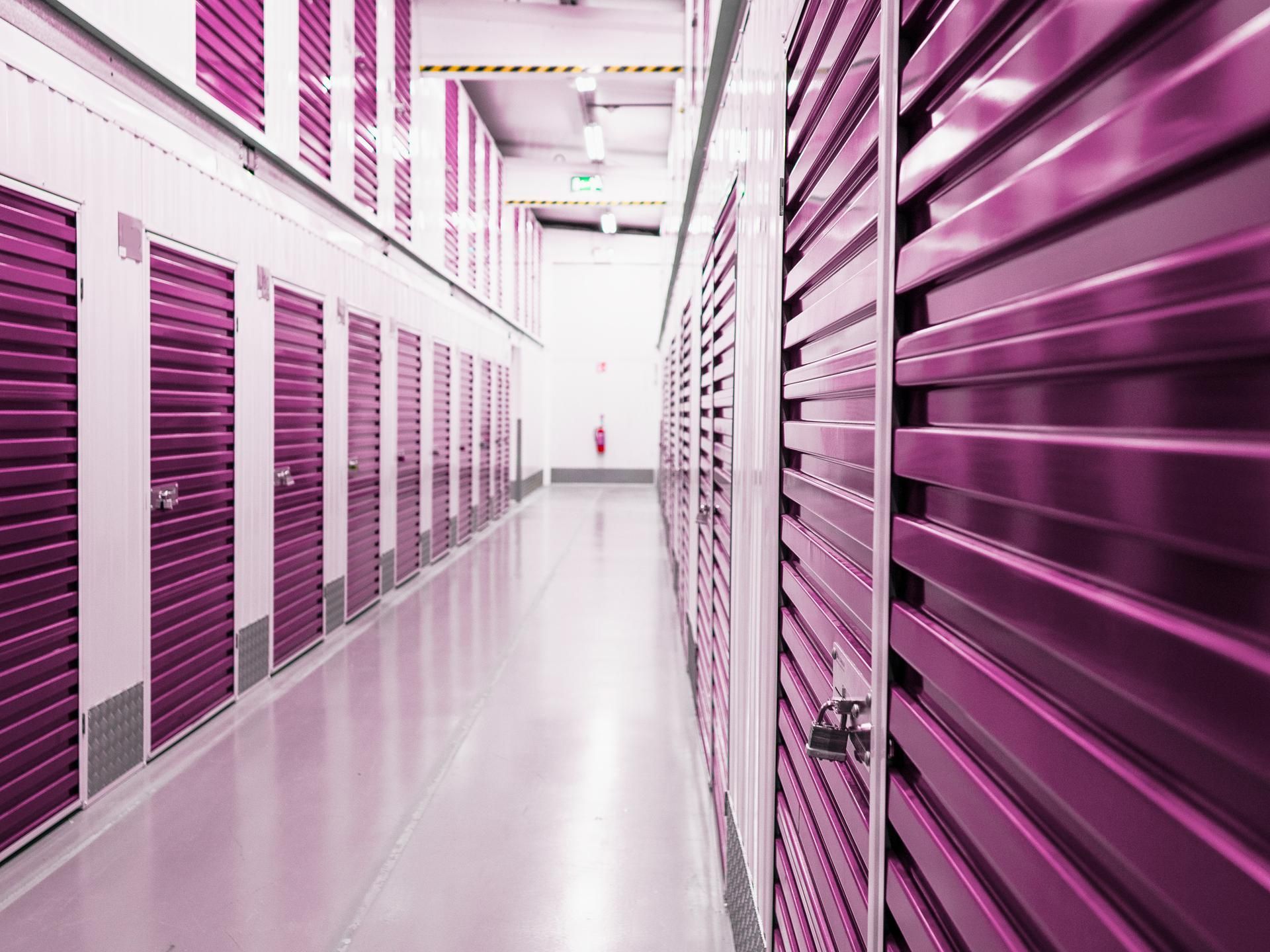 A long hallway with purple shuttered doors in a storage facility.