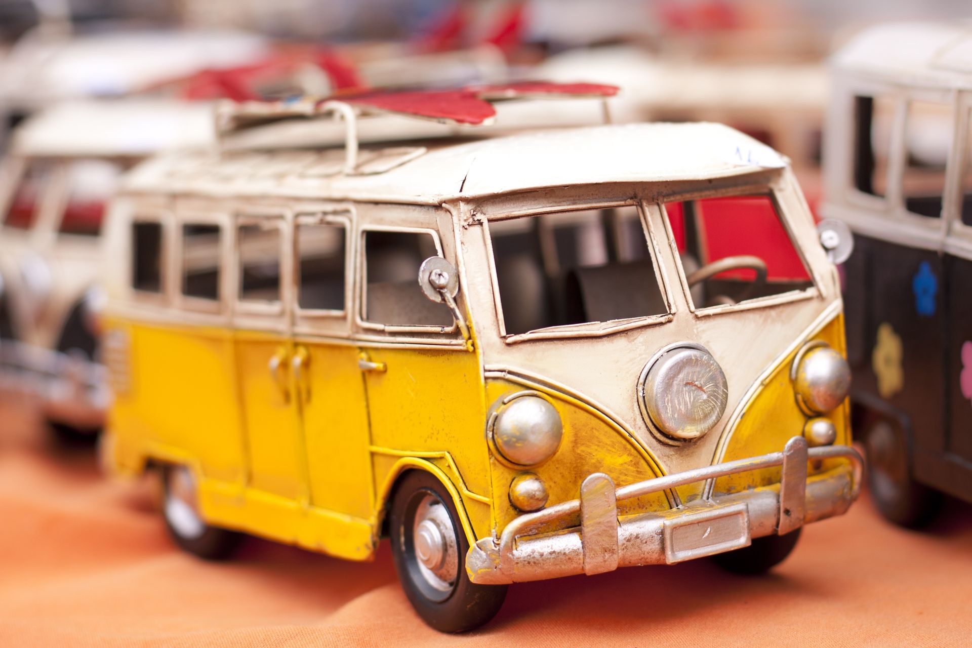 A yellow toy van with a surfboard on top of it
