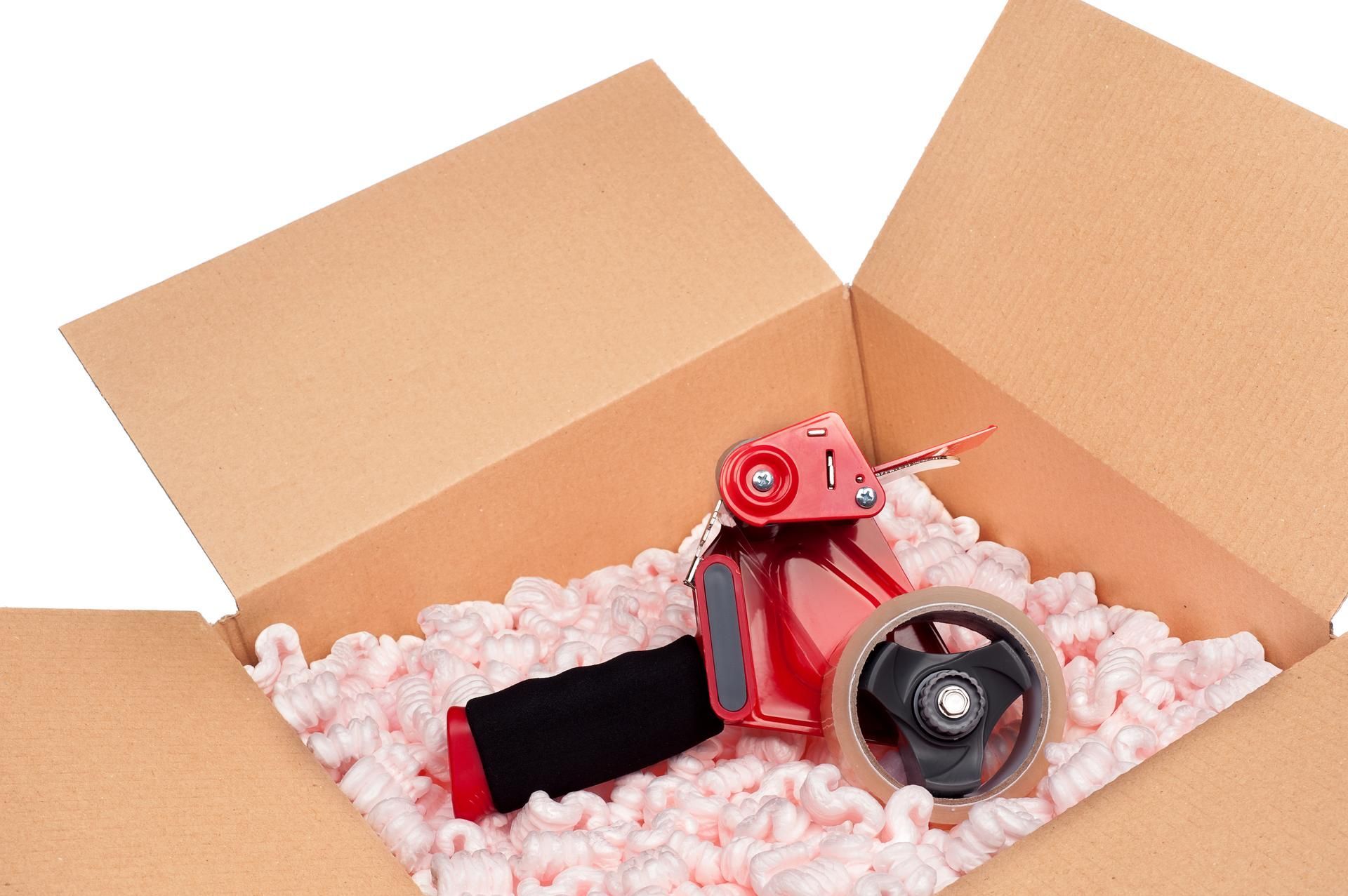A red tape dispenser is in a cardboard box