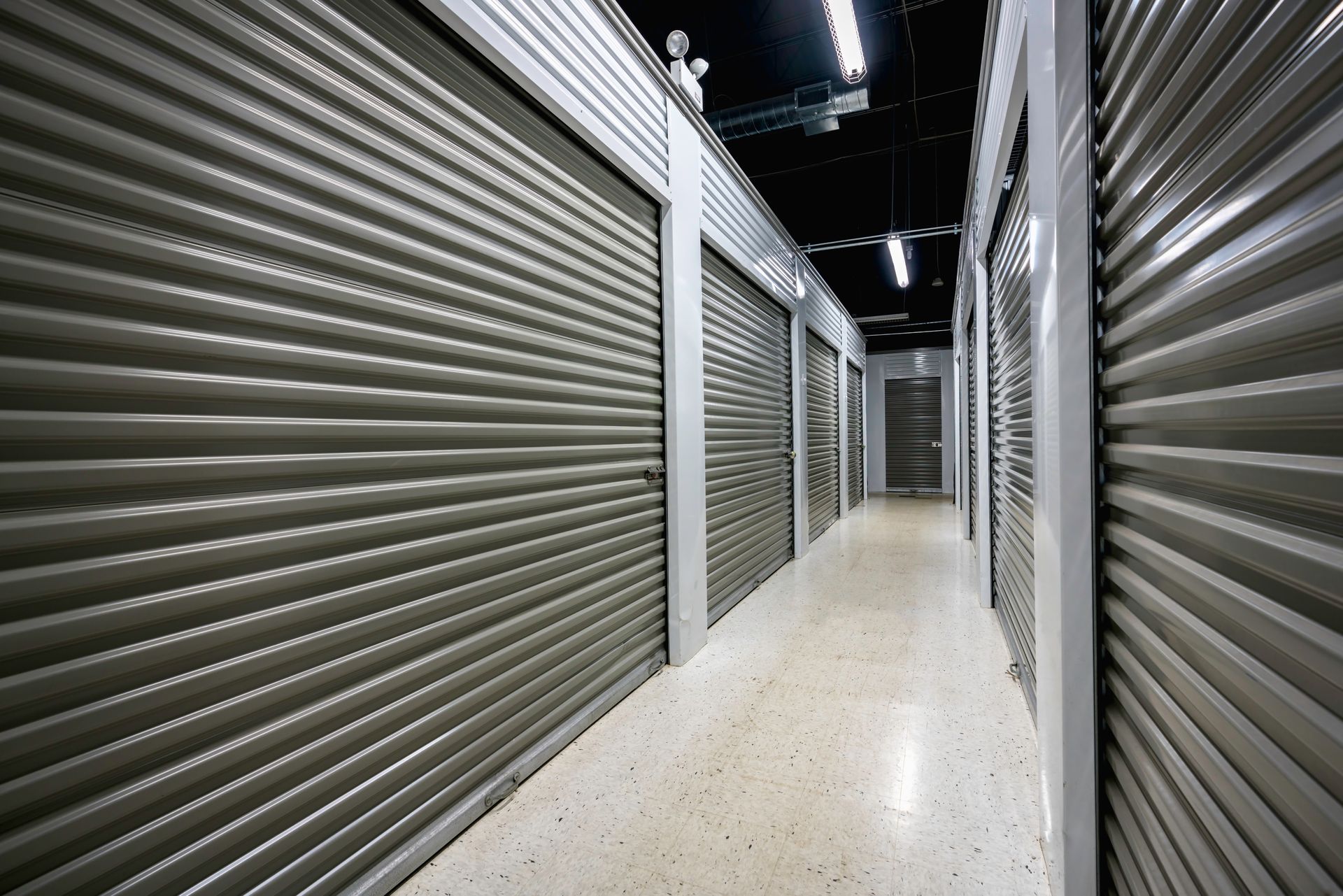 Clean hallway with secure metal roll-up doors at a modern self storage facility. Clean hallway with secure metal roll-up doors at a modern self storage facility.