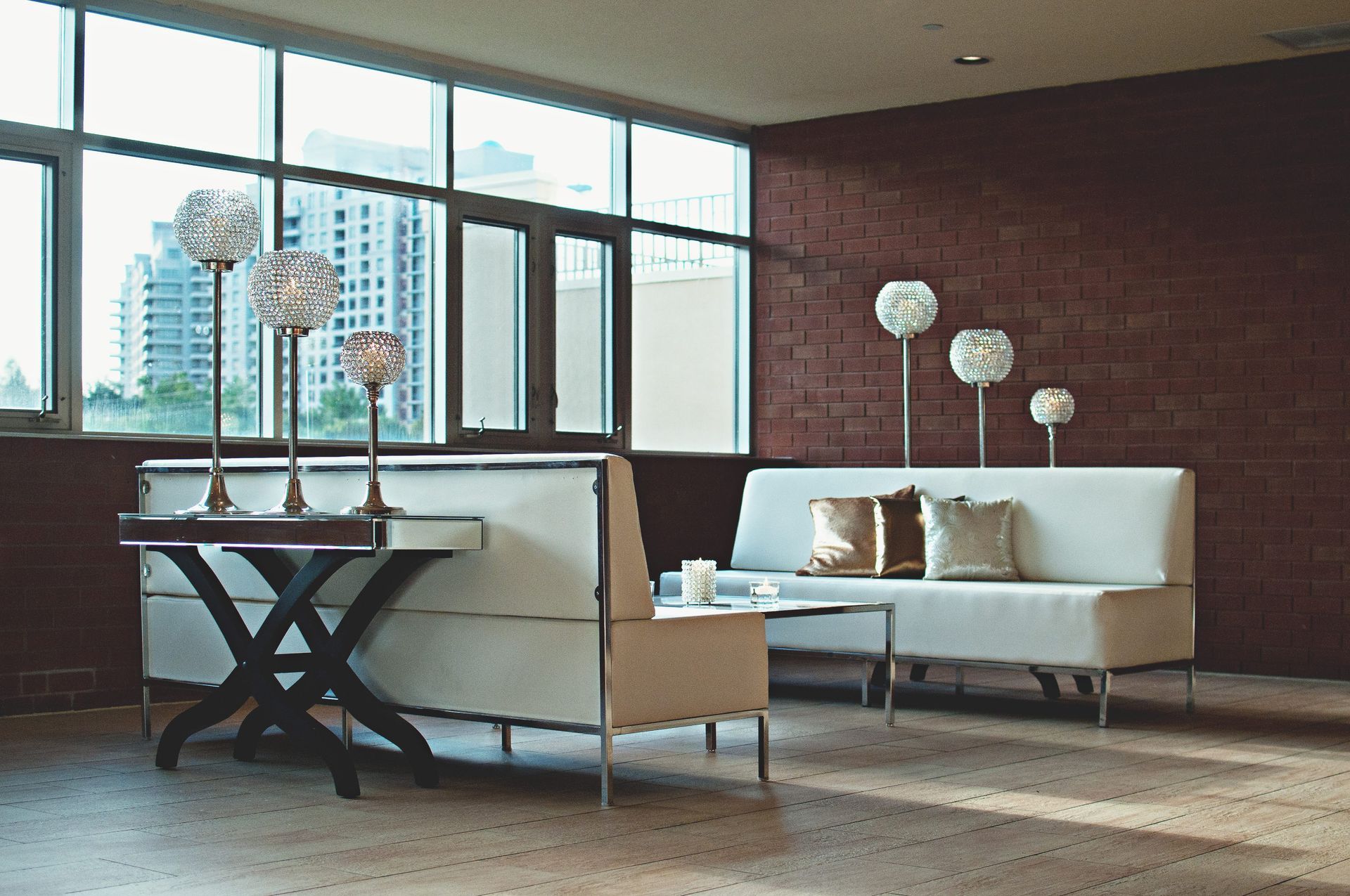 A living room with white furniture and a brick wall
