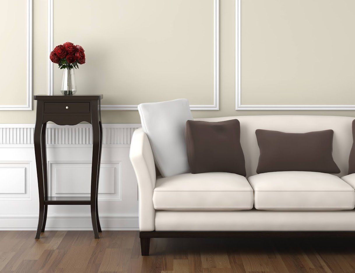 A living room with a white couch and brown pillows