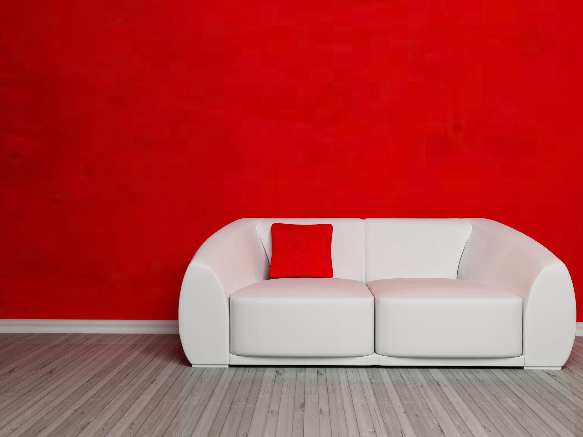 A white couch with a red pillow on it in front of a red wall