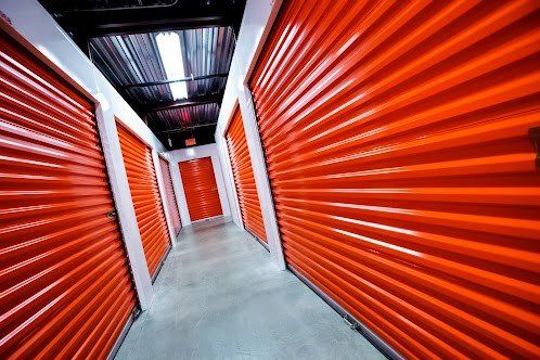 A hallway filled with orange rolling doors in a storage facility.