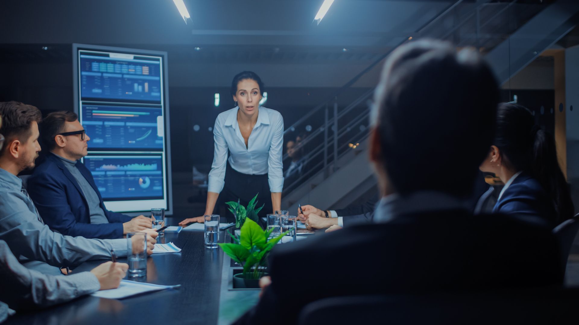 A woman is standing in front of a group of people at a conference table.