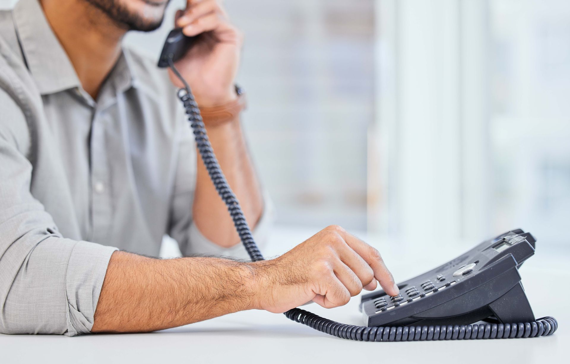 a man is sitting at a desk talking on a telephone