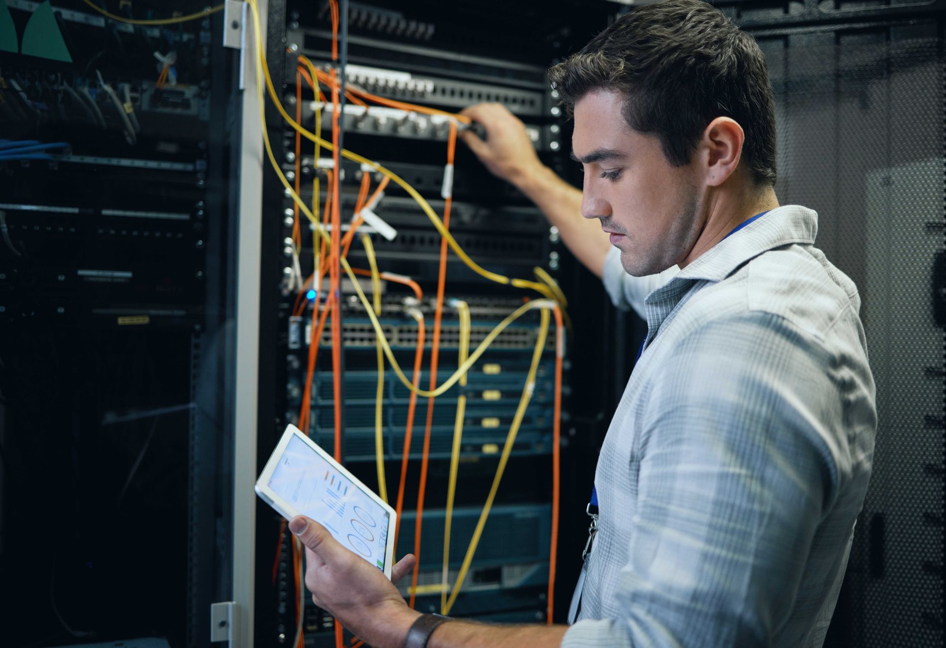 a man is working on a server in a server room while holding a piece of paper