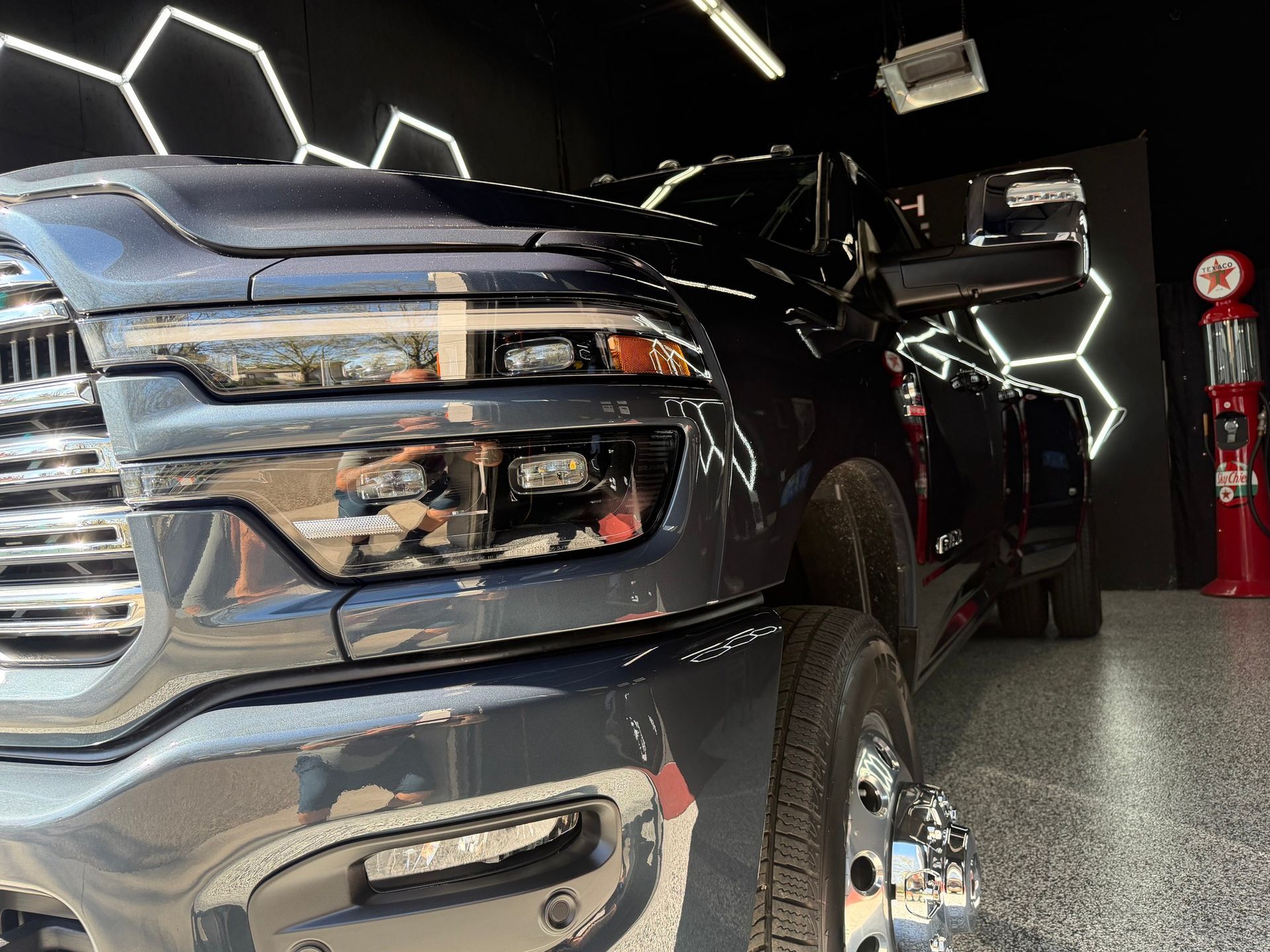 Black pickup truck in a showroom, close-up of the chrome grille and front wheel