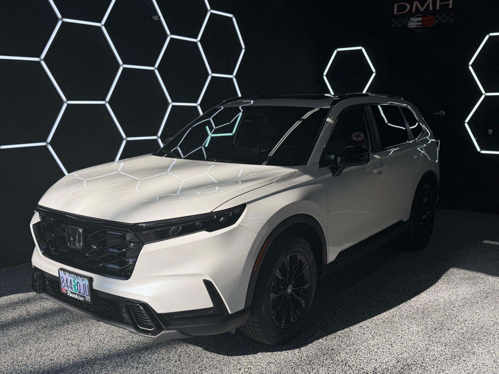 White SUV in a dark showroom with hexagonal light patterns on the wall
