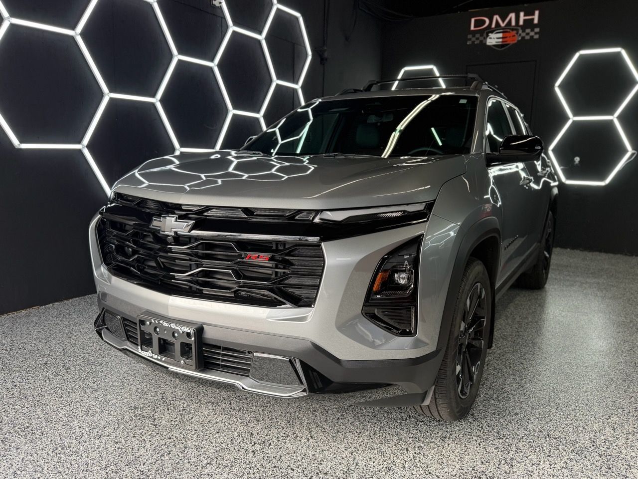 Silver SUV on display in a showroom with illuminated hexagonal wall lights