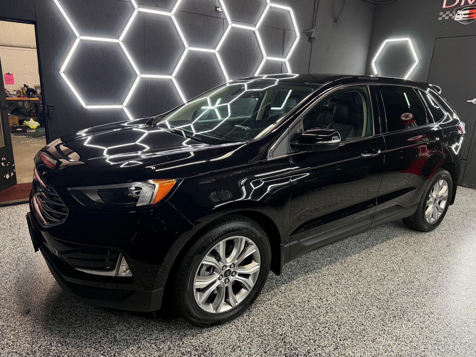 Black SUV parked indoors under bright hexagonal wall lights