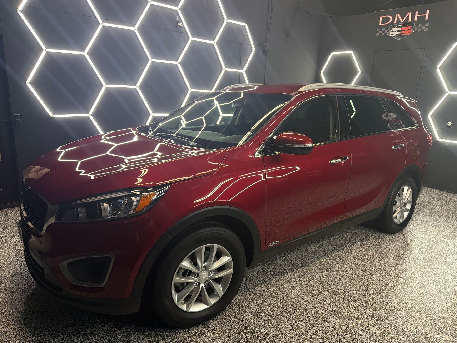 Red SUV parked indoors under hexagon wall lights in a showroom