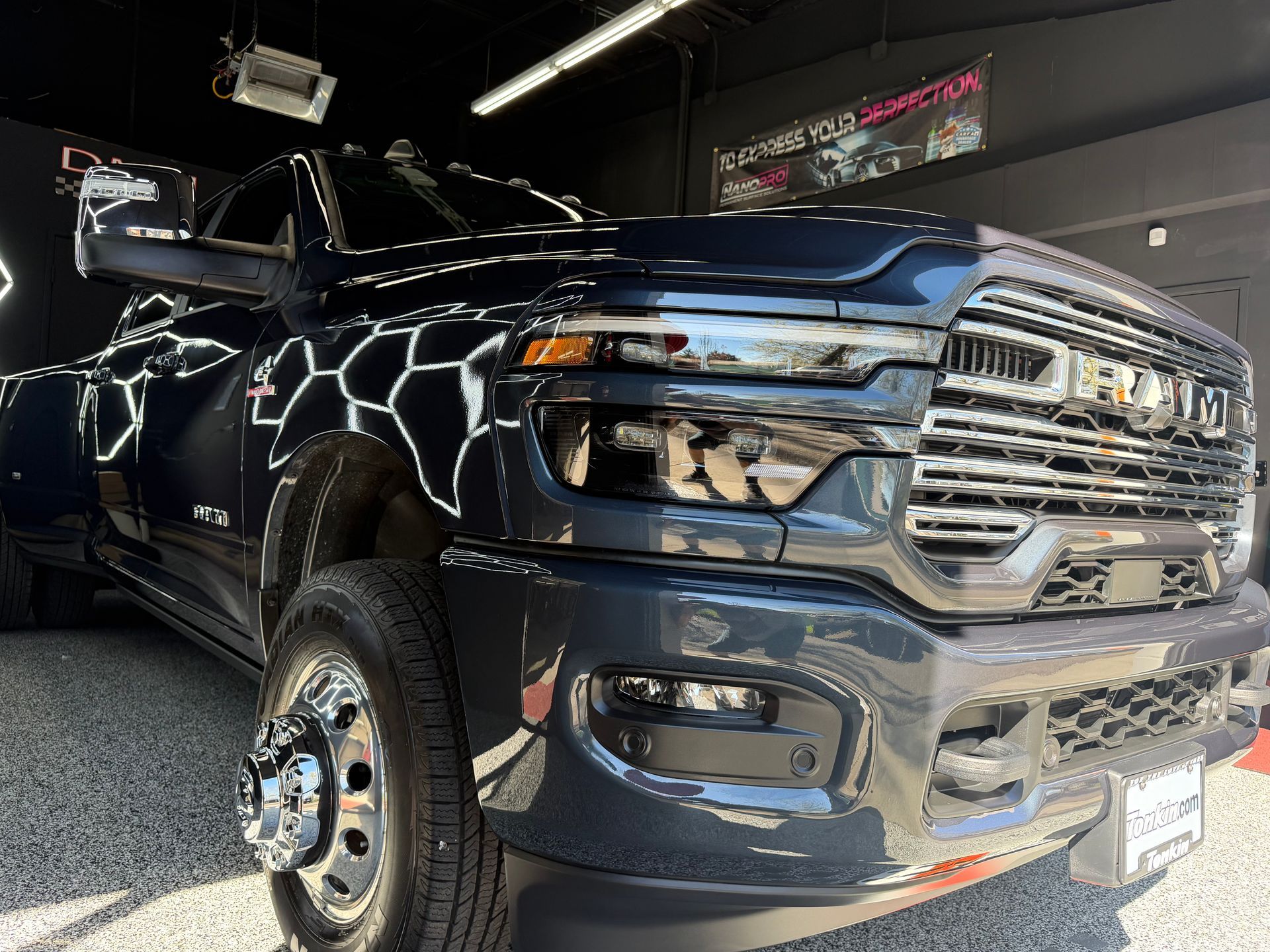 Black lifted pickup truck in a garage, front angled view with chrome grille and glossy paint reflections